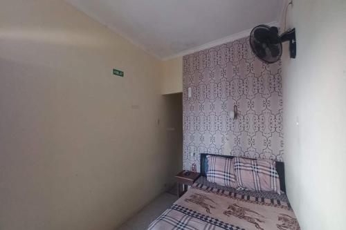 een slaapkamer met een bed en een muur bij SPOT ON 93324 Hadi Homestay Syariah in Sleman