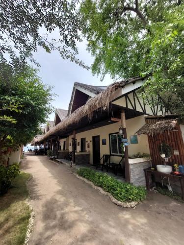 a building with a thatched roof and a dirt road at Avila's Horizon Dive Resort Malapascua in Malapascua Island