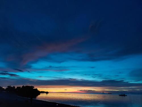 a sunset over the water with a cloudy sky at Avila's Horizon Dive Resort Malapascua in Malapascua Island