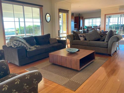 a living room with couches and a coffee table at Nirvana Farm House in Woolamai