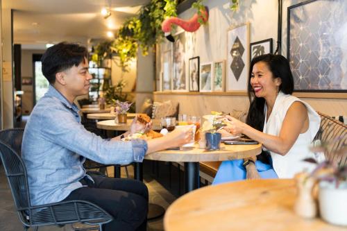 a man and a woman sitting at a table in a restaurant at Hotel Indigo Antwerp City Centre by IHG in Antwerp