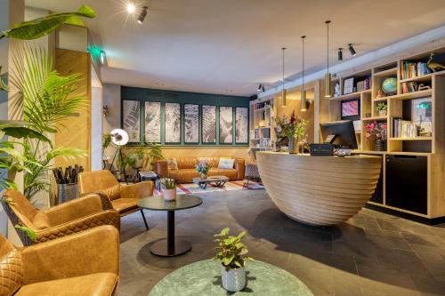 a lobby with a large couch and chairs and a table at Hotel Indigo Antwerp City Centre by IHG in Antwerp
