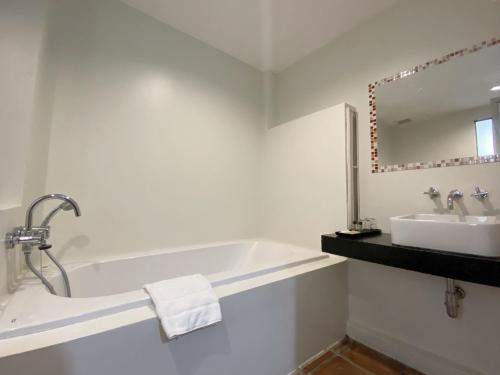 Baño blanco con bañera y lavamanos en VANA Wellness Resort, 