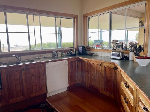 a large kitchen with wooden cabinets and windows at Nirvana Farm House in Woolamai