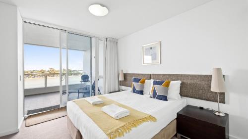 a bedroom with a large bed and a balcony at Bridgepoint 502 in Mandurah