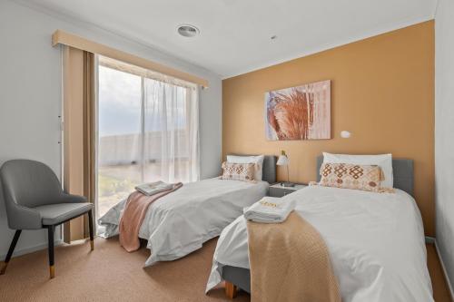 1 dormitorio con 2 camas, silla y ventana en StayAU Cozy Family Home 4BR Berwick, en Berwick