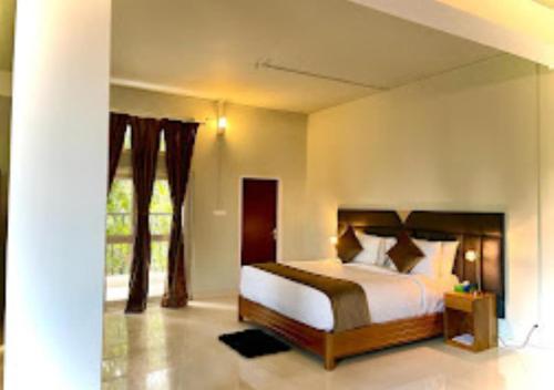 ein Schlafzimmer mit einem Bett und einem großen Fenster in der Unterkunft La Colline Resort Nagaland in Kohīma