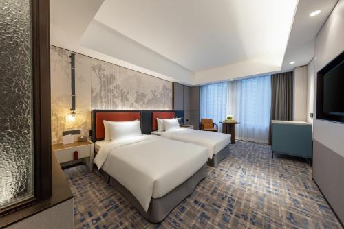 a hotel room with two beds and a television at Swissôtel Shenyang in Shenyang