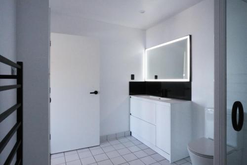 a white bathroom with a sink and a mirror at Te Wai • Luxe @ The Lake • in Queenstown