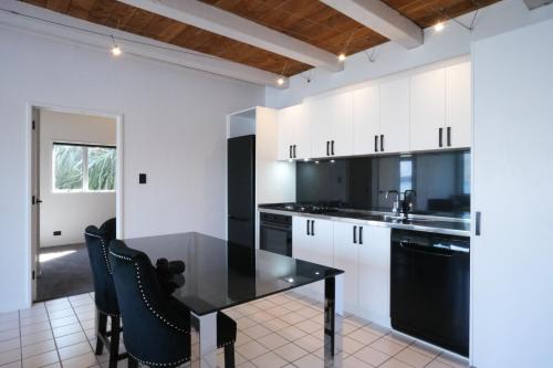 a kitchen with white cabinets and a black table and chairs at Te Wai • Luxe @ The Lake • in Queenstown
