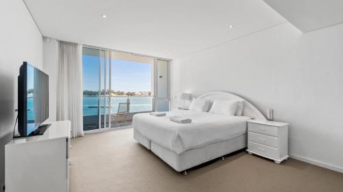 a white bedroom with a bed and a large window at Seapoint 102 in Mandurah