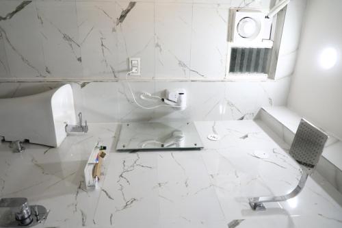 ein weiß gefliestes Bad mit einem Waschbecken und einem WC in der Unterkunft The Nectar Hotel in Hyderabad