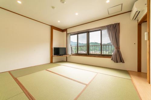 an empty room with a large window and a television at Ooedo Onsen Monogatari Premium Kinosaki in Toyooka