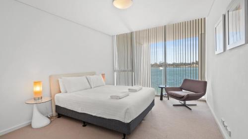 a bedroom with a bed and a chair and a window at Seapoint 109 in Mandurah