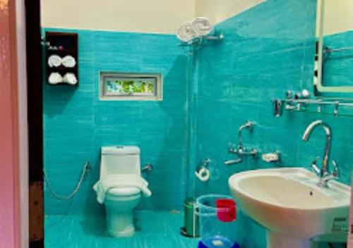a blue bathroom with a toilet and a sink at La Colline Resort Nagaland in Kohīma