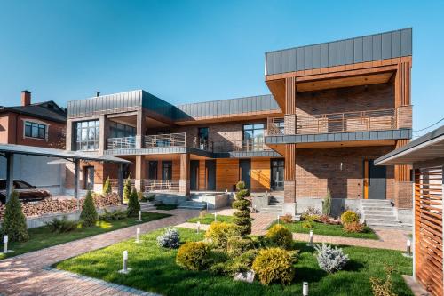 ein großes Backsteinhaus mit Garten davor in der Unterkunft Apart Hotel Colibri in Almaty