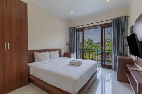 een slaapkamer met een bed, een televisie en een balkon bij Sedana Cottage in Canggu