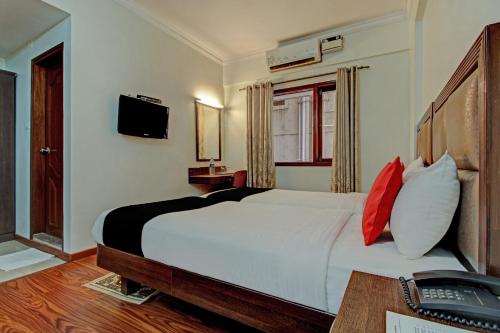 - une chambre avec un lit et un bureau avec un téléphone dans l'établissement Capital O Sri Krishna Suites Near 7d Voyage, à Bangalore