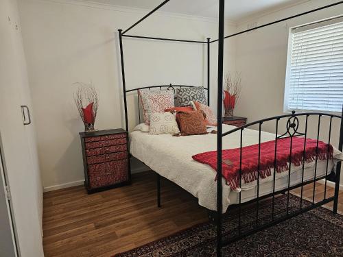 um quarto com uma cama de dossel preta com um cobertor vermelho em Family Oasis in Adelaide em Bowden
