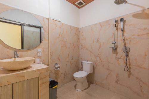 een badkamer met een wastafel, een toilet en een spiegel bij Sedana Cottage in Canggu