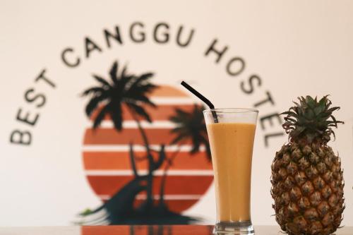 een glas sinaasappelsap naast een ananas bij Best Canggu Hostel in Canggu