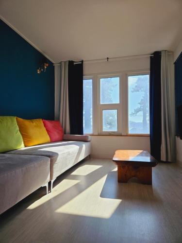 Un dormitorio con una cama con almohadas de colores y una mesa. en MO Guesthouse en Jeju