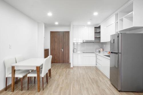 a white kitchen with a table and a refrigerator at Đà Lạt center Ho Cozy in Da Lat