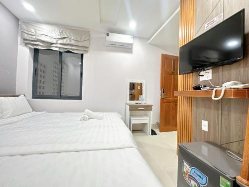 a hotel room with a bed and a flat screen tv at Milan Homestay - Milanesa Hotel and Apartment in Vung Tau