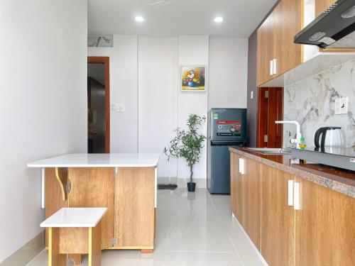 une cuisine avec des placards en bois et un comptoir blanc dans l'établissement Milan Homestay - Milanesa Hotel and Apartment, à Vung Tau
