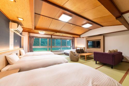 a hotel room with three beds and a tv at Ooedo Onsen Monogatari Premium Kinosaki in Toyooka