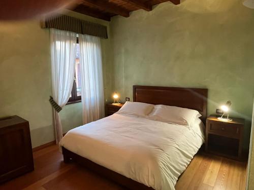 een slaapkamer met een bed met witte lakens en een raam bij 039 Maggioni B&B in Montevecchia