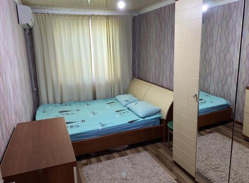 Dormitorio pequeño con cama y mesa en Мангилик ел 19, en Sätbaev