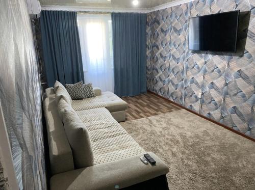 ein Wohnzimmer mit einem Sofa und einem Flachbild-TV in der Unterkunft Мангилик ел 19 in Sätbaev