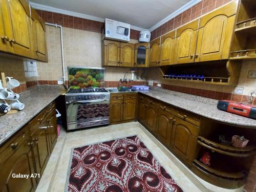 a kitchen with wooden cabinets and a red rug at Deluxe Apartment Nasr city in Cairo