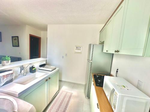 a small kitchen with a sink and a refrigerator at Apartamento com 2 dormitórios, 1 vaga de garagem e mercadinho 24hrs, em ótima localização! in Cuiabá
