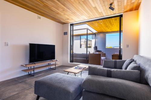 a living room with a couch and a tv at サウナ付き別荘 BBQ可能&ジャクジー付 最大12人のおしゃれな貸別荘 Blue grotto in Inbu