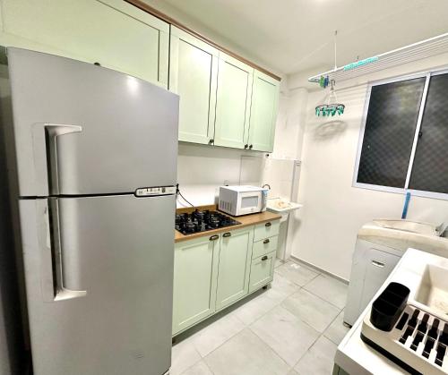 a kitchen with a stainless steel refrigerator and white cabinets at Apartamento com 2 dormitórios, 1 vaga de garagem e mercadinho 24hrs, em ótima localização! in Cuiabá