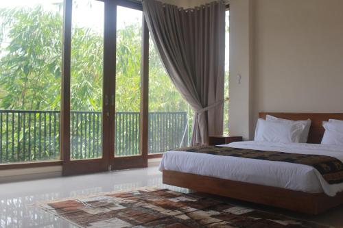 a bedroom with a bed and a balcony with windows at L'JAVAS VILLAS in Kalibendo