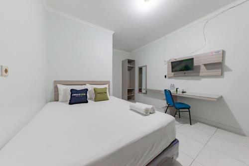 a white bedroom with a large bed and a desk at Urbanview Hotel Sunday Cirebon by RedDoorz in Cirebon