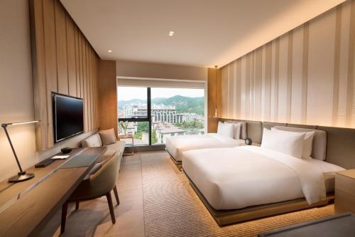 a hotel room with two beds and a desk and a television at Joyze Hotel Xiamen, Curio Collection By Hilton in Xiamen