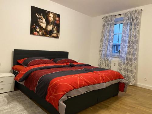 a bedroom with a bed with a red comforter at Private Wohnung direkt im Zentrum in Braunau am Inn