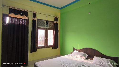 Schlafzimmer mit einem Bett mit grünen Wänden und einem Fenster in der Unterkunft OYO Fauji Villa in Kānpur