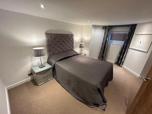 a bedroom with a bed and a lamp and a window at Spacious Central 2Bed Apartment in Wilmslow