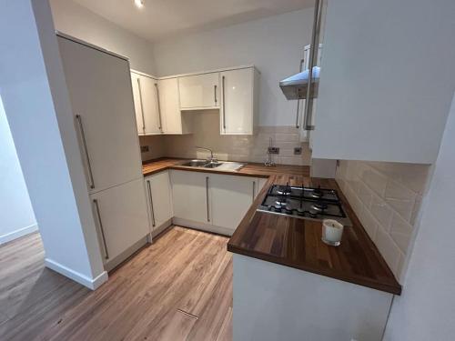 a kitchen with white cabinets and a stove top oven at Spacious Central 2Bed Apartment in Wilmslow