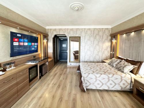 a hotel room with a bed and a flat screen tv at LAUR HOTELS Experience & Elegance in Didim