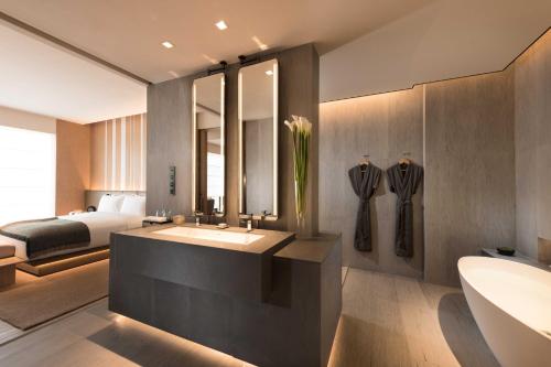 La salle de bains est pourvue d'un lavabo, d'un lit et d'une baignoire. dans l'établissement Joyze Hotel Xiamen, Curio Collection By Hilton, à Xiamen