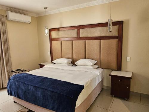 a bedroom with a large bed with a wooden headboard at Booth Suite Hotel Mafikeng in Mahikeng