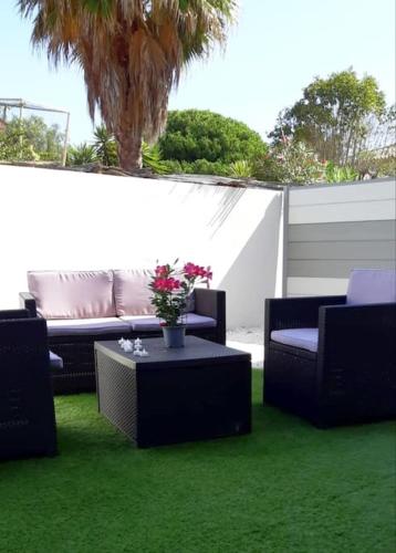 a patio with chairs and a table on the grass at Duplex 5 p 40m2 jardin de 50m2 in Six-Fours-les-Plages