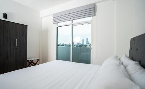 a bedroom with a white bed and a large window at Hotel Style Colombo Studio Apartment in Colombo