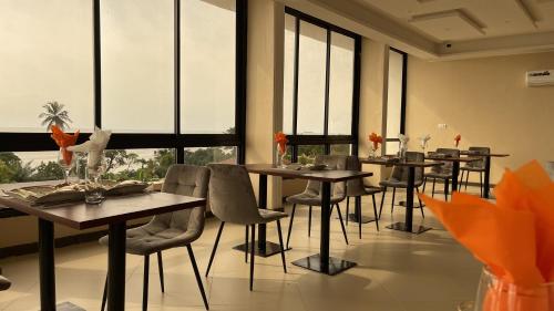 uma sala de jantar com mesas, cadeiras e janelas em SKY KENAKO HOTEL em Kribi